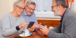Drei ältere Personen mit Smartphones an einem Tisch
