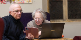 Zwei ältere Menschen an Smartphone und Computer