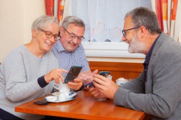 Eine Frau und zwei Herren beim Kennenlernen ihrer Handys