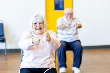 Zwei ältere Menschen machen Bewegung im Sitzen