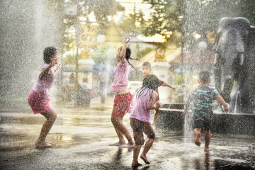 Kinder und Jugendliche erfrischen sich in einem öffentlichen Brunnen