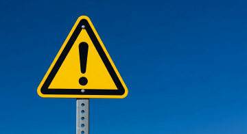 „Achtung“-Schild vor blauem Himmel